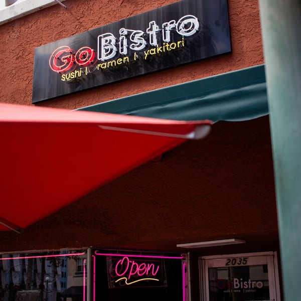 GoBistro neon sign with "sushi | ramen | yakitori" and a pink "Open" sign below.